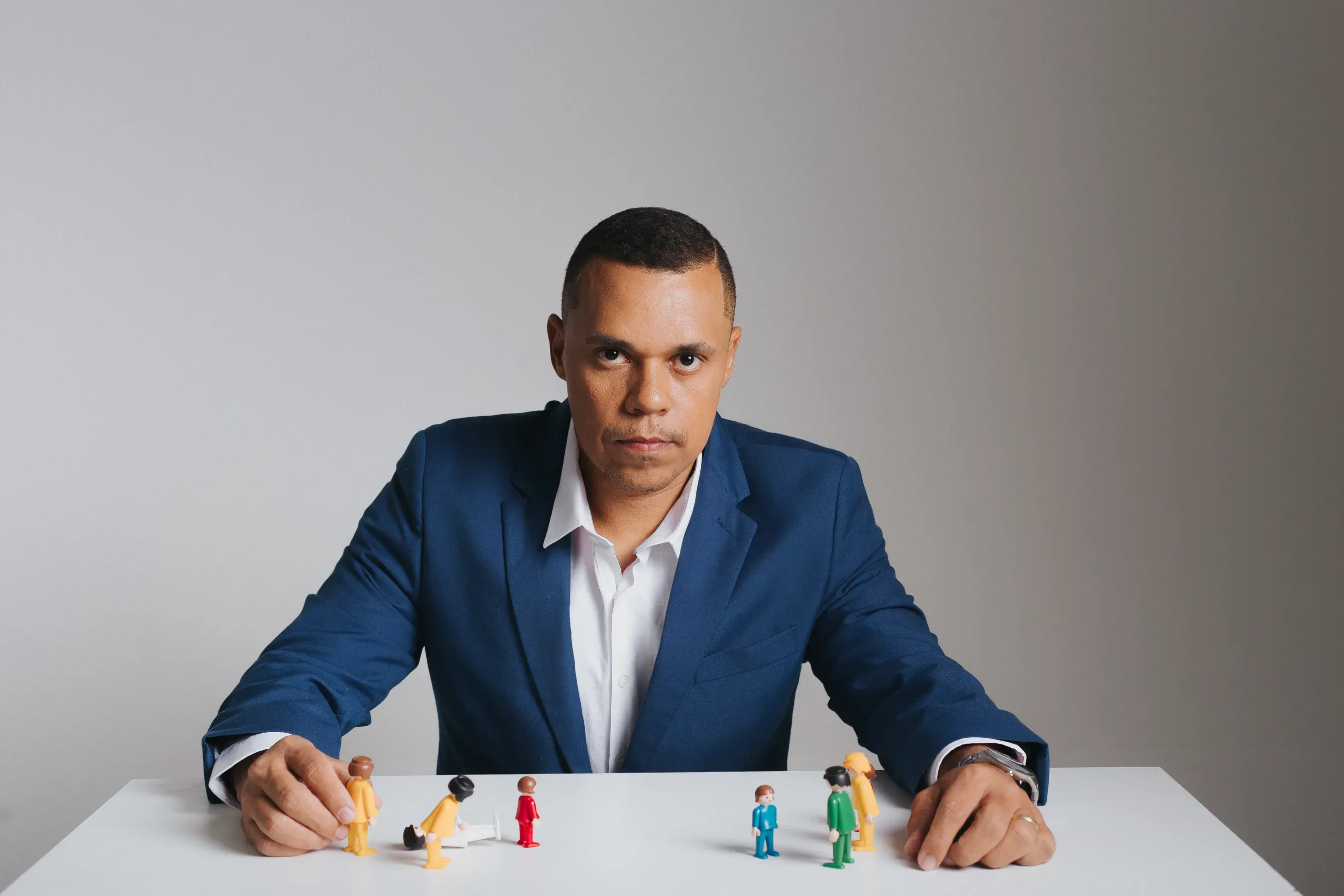 Jorge Pimenta diante de uma mesa com bonecos de constelação familiar